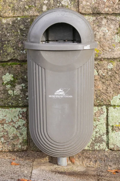 Portekiz 'de dokulu taş bir duvara karşı şehir logosu olan gri çöp kutusu.