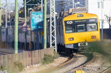 Sarı CP treni gün ışığında raylar üzerinde hareket ediyor, toplu taşımayı temsil ediyor.