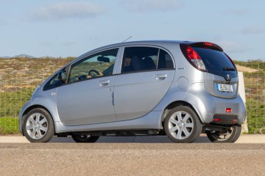 Gümüş peugeot iyon elektrikli araba bir yola park edilmiş, sürdürülebilir taşımayı temsil ediyor.