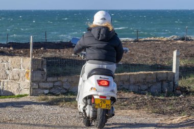 Beyaz bir Vespa 'nın 50 mobiletiyle okyanusu seyreden bir binici.