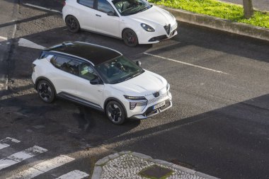 Beyaz elektrikli cip şehir caddesinde sürüyor. Havadan izleniyor.