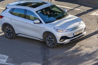 Gümüş renkli bir SUV model. Hava manzaralı bir caddede sürüyor.