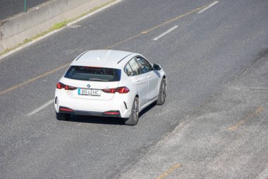 Otoyolda giden beyaz BMW arabası, ulaşım ve seyahat temalarını betimliyor