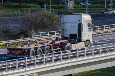 Yarı kamyon boş bir karavanı köprüden taşıyor, lojistiği simgeliyor.