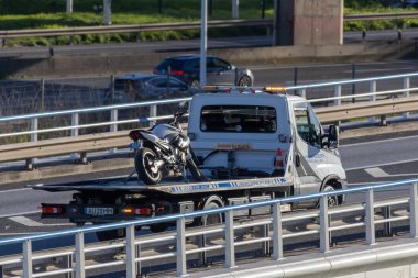 Çekici yolda gidiyor, bir arızadan sonra kurtarılmış bir motosiklet taşıyor.