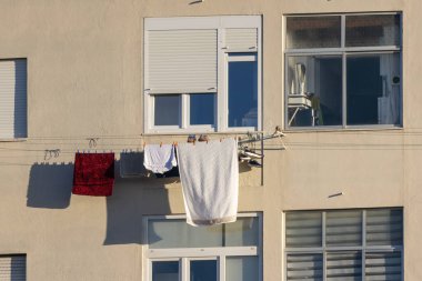 Temiz çamaşırlar bir apartmanın çamaşır ipinde gün ışığında asılı.