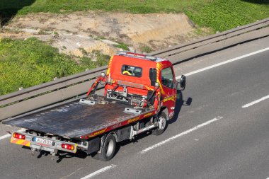 Kırmızı çekici çok şeritli bir otoyolda gidiyor, otomotiv yardımı sağlıyor.