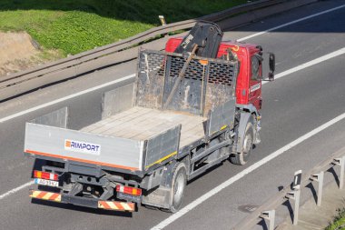 Kırmızı ticari kamyon ve vinç otobanda mal taşıyor.