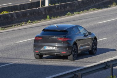 Havadan bakıldığında çok şeritli bir otoyolda giden elektrikli bir araç.