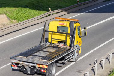 Sarı düz kamyonlu kiralık kamyon, hava manzaralı çok şeritli bir otoyolda ilerliyor.