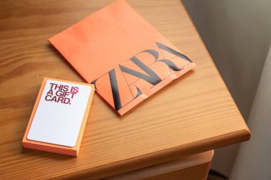 Zara hediye kartı ve ahşap bir yüzey üzerinde turuncu zarf sunmaya hazır.