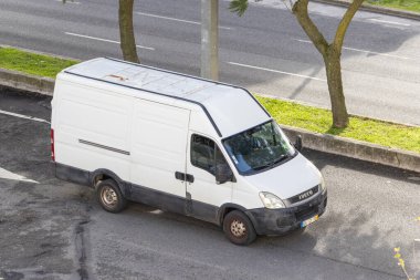 Beyaz fildişi dağıtım minibüsü asfalt yolda ilerliyor. Şehir ortamında.