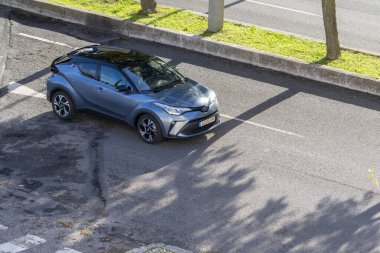 Toyota c hr hibrit araba gri asfalt bir sokakta park edilmiş ağaç gölgeleri ile