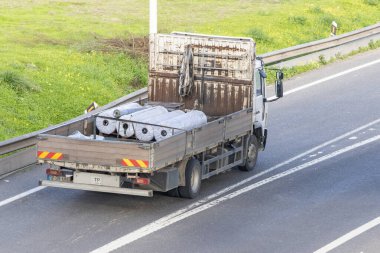 Yolda ilerleyen inşaat malzemelerini taşıyan eski bir kamyon.