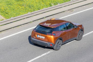 Bronz peugeot 2008 SUV, modern ulaşım ve hareketliliği temsil eden bir otoyol boyunca seyahat ediyor.