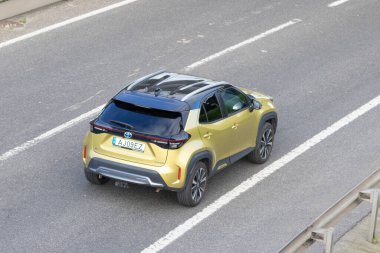 Modern Toyota Yaris, hava perspektifinden asfalt bir yolda giden melez bir araç.