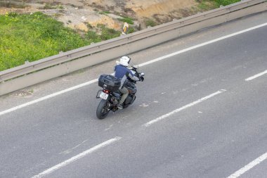 Motosikletçi, modern bir otoyolda bavul kutularıyla motosiklet sürüyor.