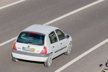 Yüksek bir perspektiften, güneşli bir günde otobanda seyahat eden beyaz bir araba.