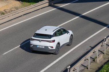 Beyaz Volkswagen id.4 elektrikli cip çok şeritli bir otoyolda ilerliyor.