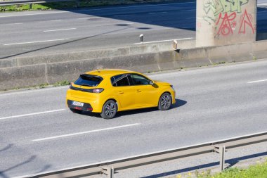 Sarı peugeot 208 hızlı hareket ve ulaşımı temsil eden bir şehir otoyolunda gidiyor.