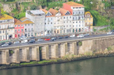 Ribeira bölgesinde nehir kenarındaki yolda giden arabalarla tarihi mimari sergileniyor.