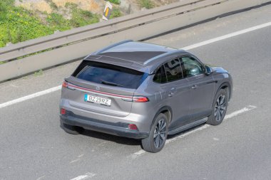 Gri modern arazi aracı hava manzaralı bir caddede ya da otoyolda seyahat ediyor.