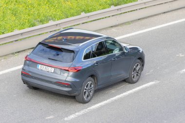 Koyu gri audi q4 e tron SUv bir otoyolda hava perspektifinden gidiyor.