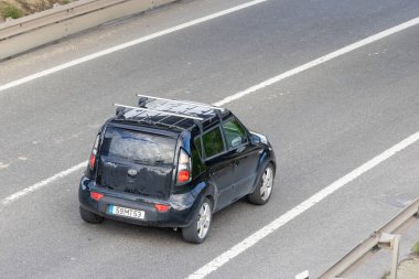 Çatı rafı olan siyah Kia Soul Car havadan bakıldığında çok şeritli bir otoyolda seyahat ediyor.