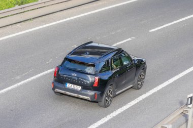 Beyaz çizgileri olan asfalt bir otoyolda giden siyah bir vatandaş arabası.