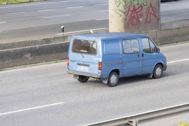 Mavi kargo kamyonu beton bir otoyolda köprü sütununun yanında ilerliyor.