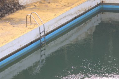 Parktaki sakin bir yüzme havuzunda kent mimarisini yansıtan berrak su yer alır.