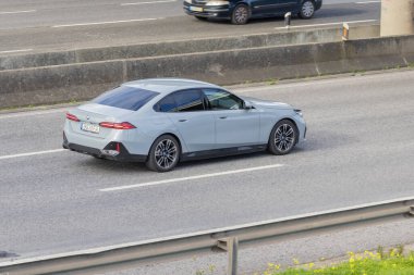 Modern açık gri BMW araba, yüksek manzaralı çok şeritli otoyolda gidiyor.