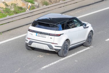 Beyaz Range Rover 'ı, asfalt bir yolda giderken havadan bakıldığında...