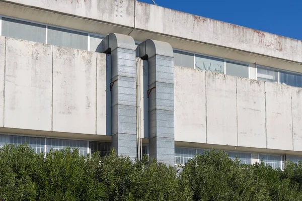 Endüstriyel bina cephesi mavi gökyüzüne karşı iki havalandırma kanalı sunuyor.