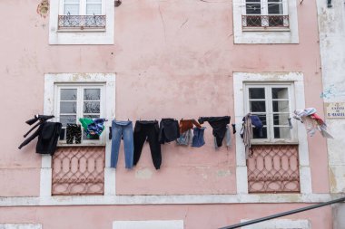 Tarihi bir Avrupa şehrinin yıpranmış pembe binasında çeşitli çamaşır ipleri asılı.