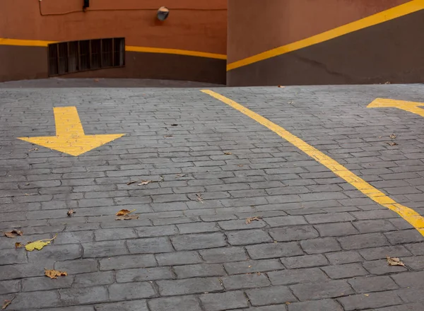 Fragment of an urban brick road marked with yellow arrows.