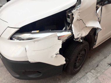 Beyaz bir araba parçası, kazadan sonra hasar görmüş, sokakta duruyor..