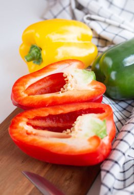 Dilimlenmiş taze kırmızı biberler mutfaktaki masanın üzerindeki tahta kesme tahtasının üzerinde..