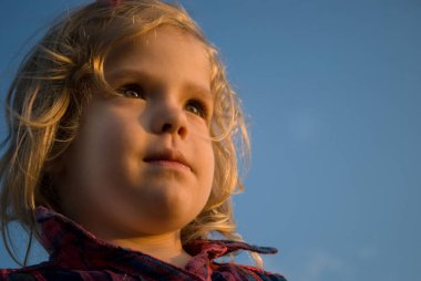 Kız güneşin derinliklerine bakıyor. Sağlıklı, sarışın, güzel görünümlü.