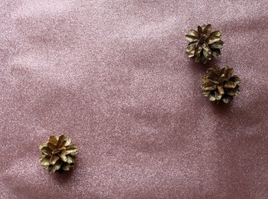 Parlak pembe bir Noel arkaplanı ve boyalı altın koniler.