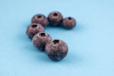 Yaban mersinleri açık mavi arkaplanda yarım kalp şekli oluşturur.