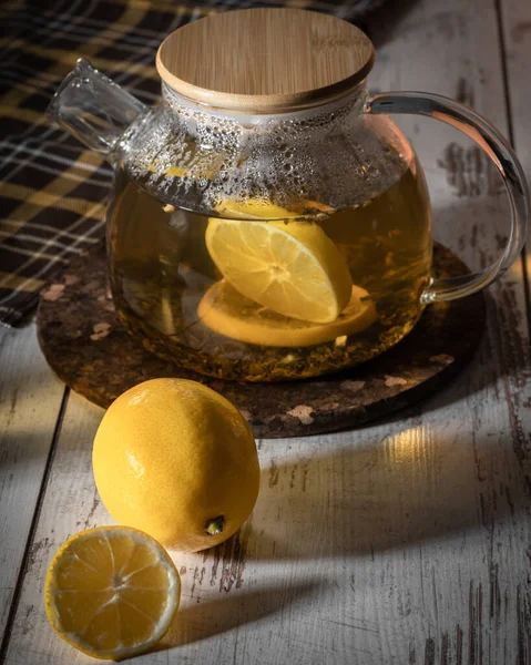 Healthful herbal tea with lemon in the glass teapot, hot tea drink