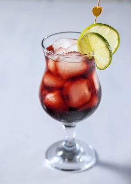 Nar şuruplu taze kırmızı alkollü kokteyl, votka ve sprite, bardakta buz kokteyli, yakın çekim ve seçici odaklanma.