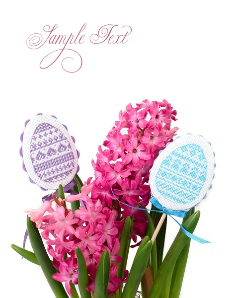 Rosa hyacinter och dekorativa broderade ägg på pinnar på en vit bakgrund. En påsk bakgrund med plats för text. — Stockfoto