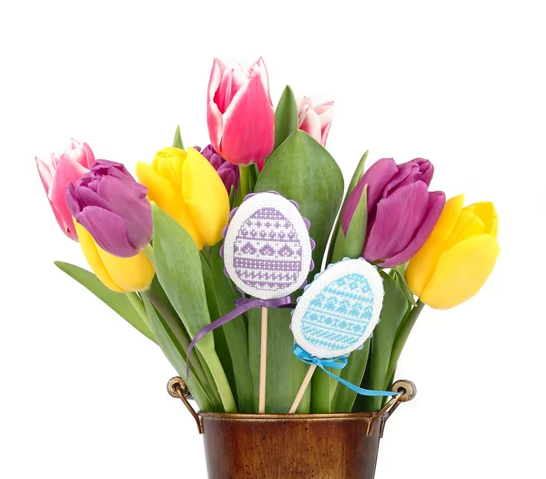 Bright spring tulips and the embroidered Easter eggs on sticks on a white background. An easter background with space for the text. — Stock Photo, Image