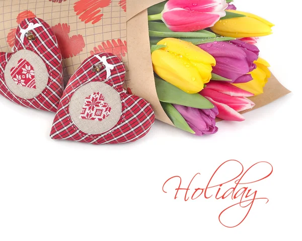 Bouquet of bright spring tulips and two textile hearts on a white background with space for the text. — Stock Photo, Image