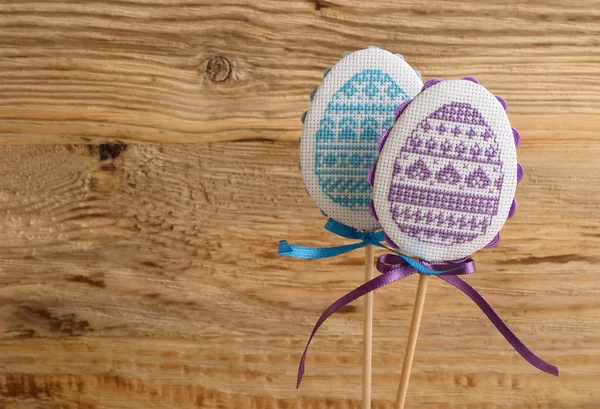 Wielkanocny dekoracyjny haftowany jajko na pałeczka na jasnodrewniany tło. Tło wielkanocne z miejscem na tekst. — Zdjęcie stockowe