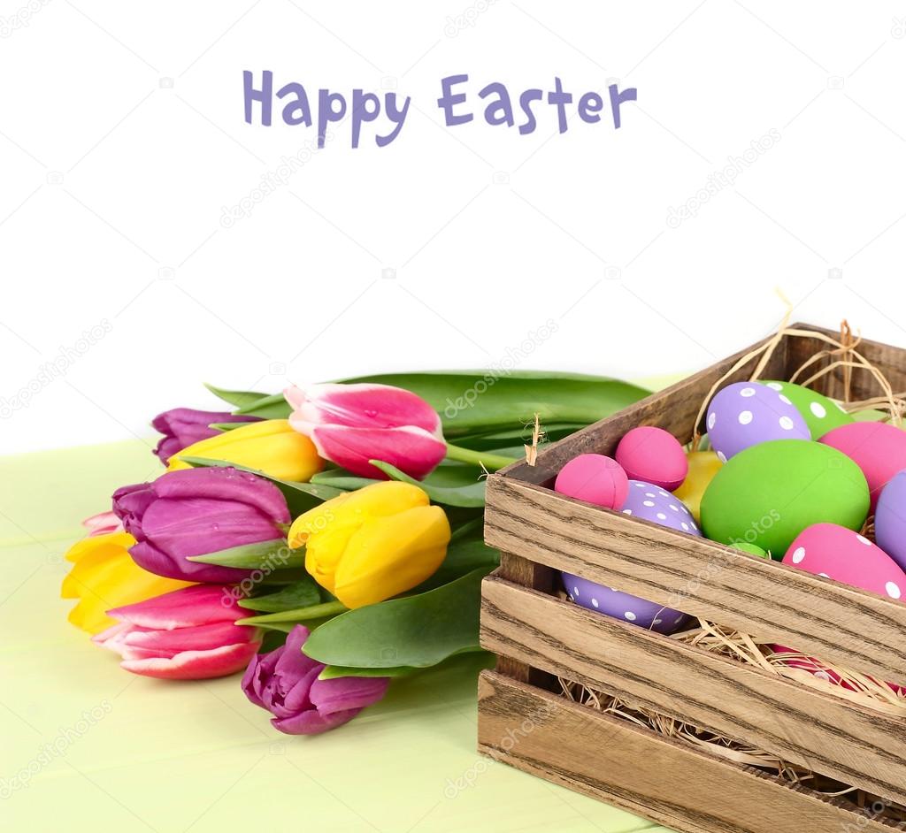 Bright spring tulips and Easter eggs in a wooden box on a white background. An easter background with the place for the text.
