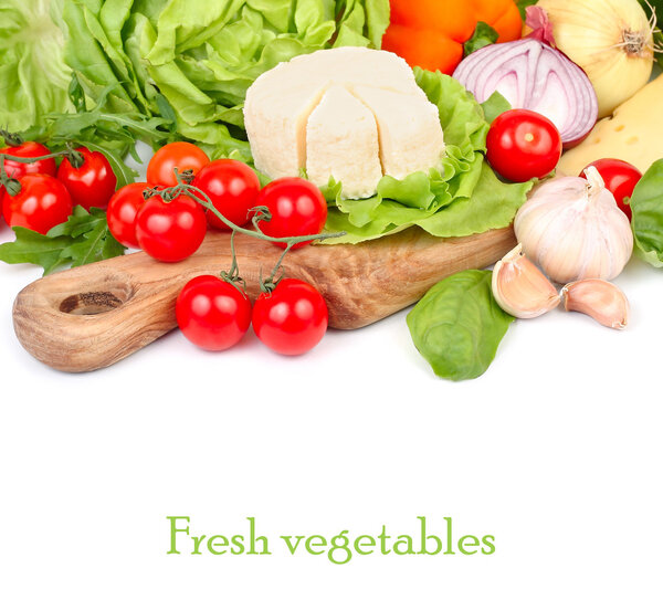 Cheese, fresh tomatoes and other vegetables on a wooden board on a white background with space for the text.