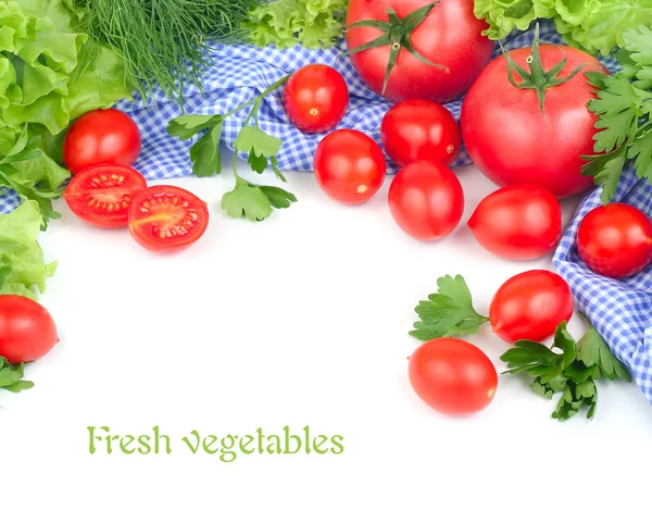 Frische Tomaten und Kirsche und Grüntöne auf einer blau karierten Serviette auf weißem Hintergrund mit Platz für den Text. — Stockfoto
